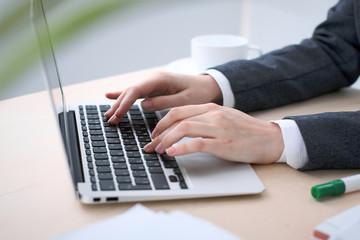 Close-up of business woman  hands  typing on  laptop computer in the white colored office.