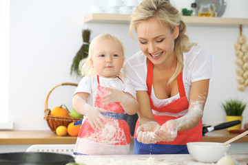 Mother and little daughter are cooking in the kitchen. Spending time all together or happy family concept