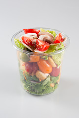 Plastic transparent fresh containers with salad on a glass table