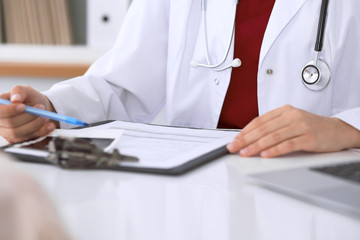 Close up of a female doctor pointing into an application form while consulting patient