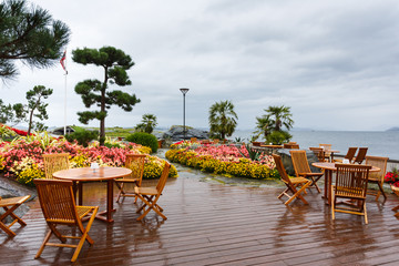 Fototapeta na wymiar Open air cafe in the garden on a shore of island in Norway, rainy weather