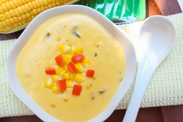 Corn soup and tomato in white bowl on  wooden background.closeup