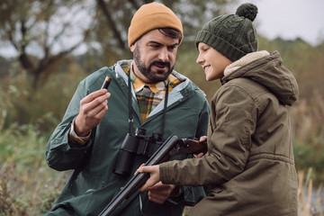 Father showing how to load bullet in gun