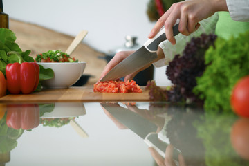 Closeup of human hands cooking vegetables salad in kitchen on the glass  table with reflection