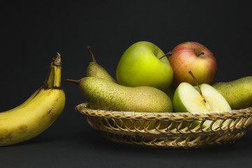 Still life with fruit basket, pears, apples and bananas isolated on gray