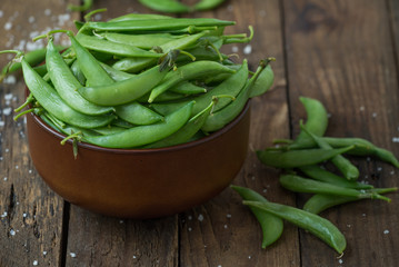 Green pea in bowl on rustic wooden background

