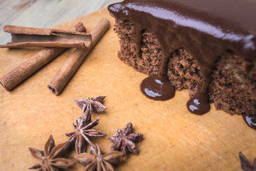 Chocolate cake, cinnamon sticks and anise star on a wooden background