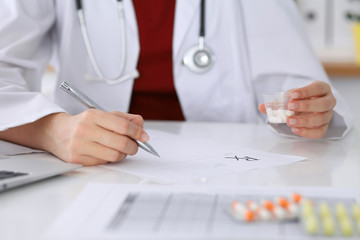 Female medicine doctor fills up  prescription form to patient closeup. Panacea and life save, prescribe treatment, legal drug store, contraception concept