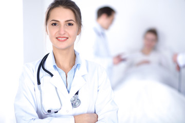 Fototapeta premium Female doctor smiling on the background with patient in the bed