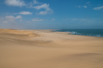 Fototapeta na wymiar View towards Walvisbay from sand dune near Swakopmund, showing sea edge and oil drill towers