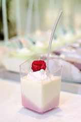 Delicious Italian dessert Panna Cotta with raspberry and cream  served in small transparent glass vessel