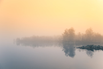 Fototapeta premium A beautiful morning scenery at the lake in Norway. Tranquil autumn landscape. Rock formation in a foreground. Colorful landscape with mist.