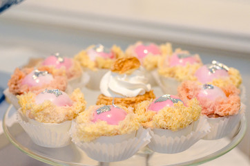 Delicious wedding reception glaze pink candy sweet desserts cakes on glass plate with edible flaked leaf of silver. Candy bar dessert.