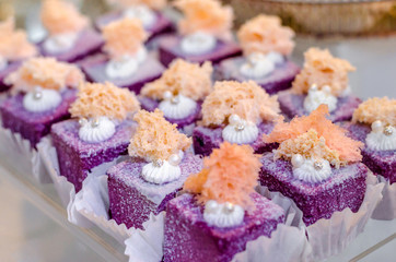 Delicious wedding reception sweets luxury purple color desserts with edible pearl and edible crystal stones on top on glass plate. Candy bar desser.