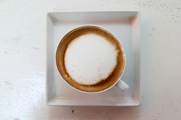 Hot cappuccino on white tray in morning time.