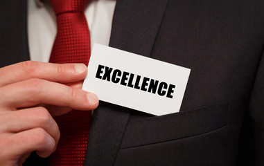 Businessman putting a card with text EXCELLENCE in the pocket