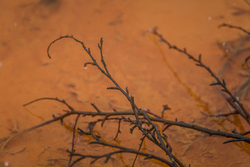 An orange rusty water at the old copper mine in Norway in winter. Bright color stream details, closeup.