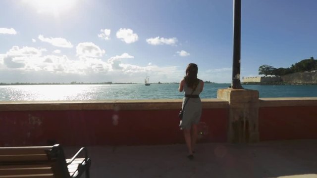 Woman walking to take a picture of the ocean in Old San Juan, Puerto Rico