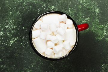 Cup of hot chocolate with marshmallow for Christmas on a green background. Top view