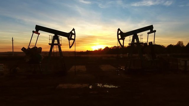 moving between two working oil pumps against sunset, 4k
