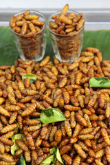 Street food, fried silk worms with lime leaf on banana leaf ready for sale.