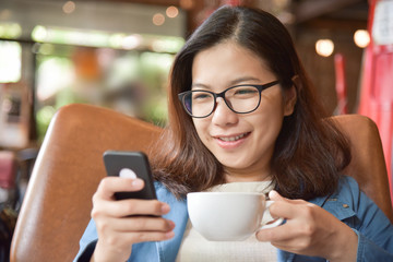 Woman holding cup of coffee and using smart phone.