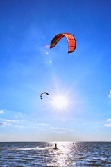 Man riding a kite surfing on the waves in the summer.