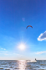 Man riding a kite surfing on the waves in the summer.