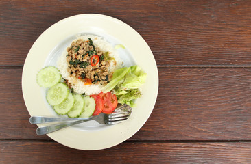 Thai cuisine, rice with stir-fried pork and basil on white plate.