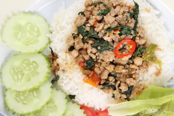 Thai cuisine, rice with stir-fried pork and basil on white plate.