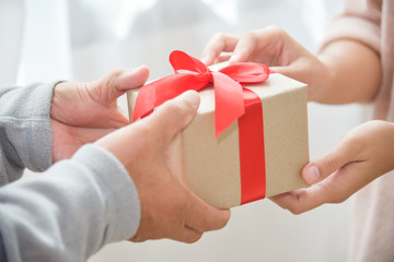 Asian woman giving a brown gift box to elderly man.