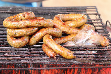 Thai cuisine, grilled Thai sausages Northern style on stove at market.