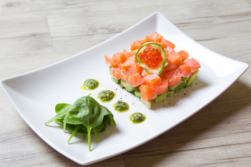 Tartare from salmon, caviar and avocado with pesto sauce and spinach. Close-up, selective focus.