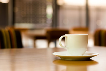 a white cup of tea or coffee on a wooden table in a Cafe close-up with copy space