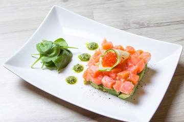 Tartare from salmon, caviar and avocado with pesto sauce and spinach. Close-up, selective focus.