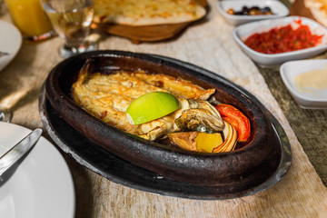 Appetizing baked hot fish freshwater trout entirely in a dish on a table in a restaurant with fresh lemon or lime