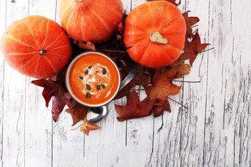 Roasted pumpkin and carrot soup with cream and pumpkin seeds on wooden background