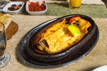 Appetizing baked hot fish freshwater trout entirely in a dish on a table in a restaurant with fresh lemon or lime