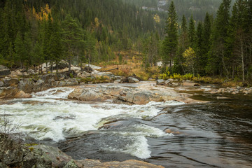 A beautiful waterfall in a central Norway. Colorful autumn landscape at the river. Natural fall scenery.