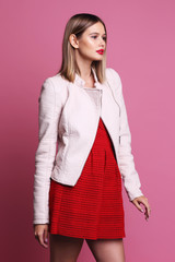 Fashion portrait of young woman in pink leather jacket and red dress.
