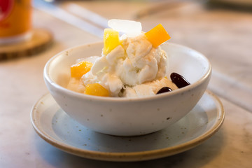 Cup of coconut ice-cream , Thai style, and fruit topping on a wooden table in a restaurant