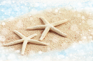 Fototapeta na wymiar Starfish relaxing on beach, beige sand sea water bokeh light sparkling effect. Soft faded tones.