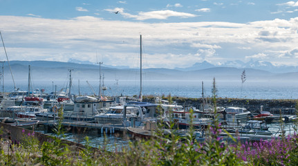 Fototapeta na wymiar Yachts and boats on a mooring on a background of cloudy sky and mountains