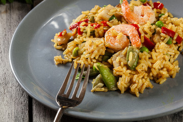 Traditional seafood paella with shrimp, fish and chicken seved in plate.