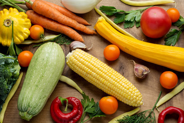 Raw organic vegetables with fresh ingredients for healthily cooking on wooden background, top view, banner. Vegan or diet food concept.