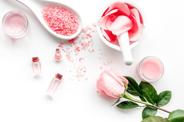 Make cosmetics with rose  oil. Mortar with rose petals and pestle on grey stone background top view copyspace