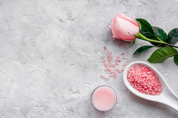 Products for skincare based on rose oil. Cream and spa salt on grey background top view copyspace