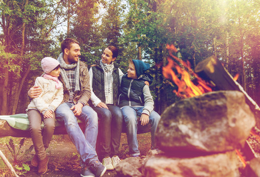 happy family sitting on bench at camp fire