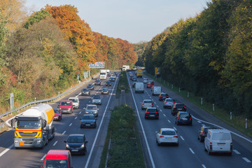 Autobahn mit Feierabendverkehr am schattigem Waldrand
