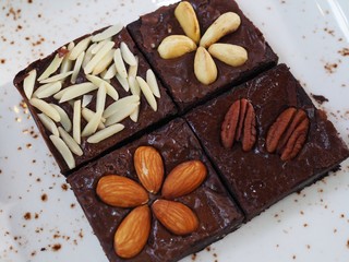Variety of Brownies include Almond Macadamia Peanut and Chocolate Chip on the white dish and wood table from above view